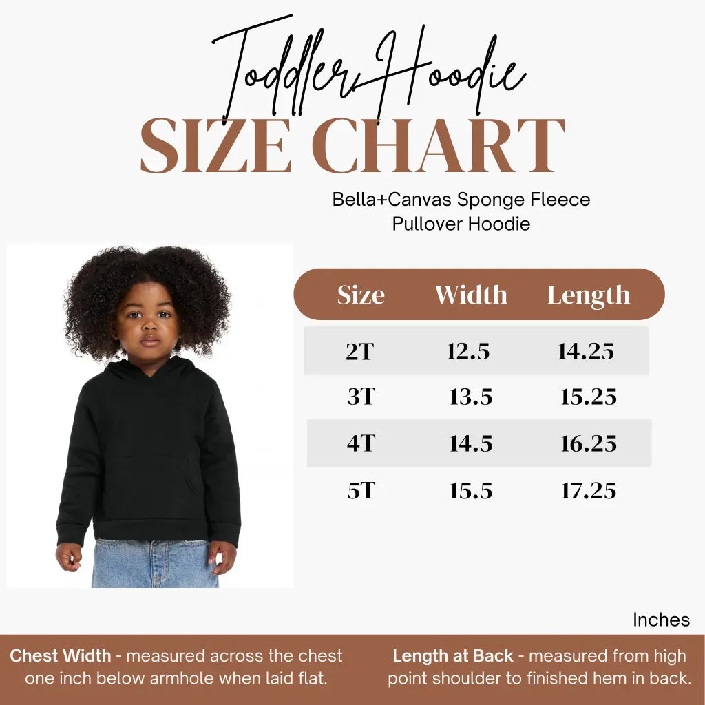 A child wearing a black Uniquely Human Toddler Hoodie next to a size chart table listing width and length measurements in inches for sustainable toddler sizes 2T through 5T.