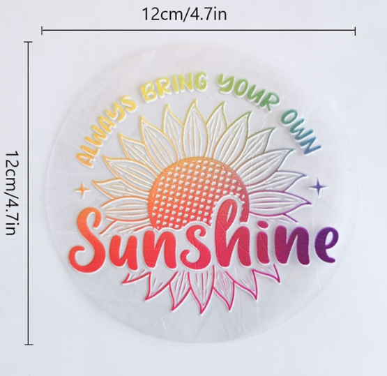 Add a burst of positivity to any space with the Sunshine Suncatcher by RainBee Designs LLC—a round window decal featuring a cheerful sunflower and bright rainbow-colored text, “Always bring your own Sunshine.” Measuring 12 cm (4.7 in) in diameter, this sticker is perfect for windows and brings uplifting vibes wherever it’s displayed.