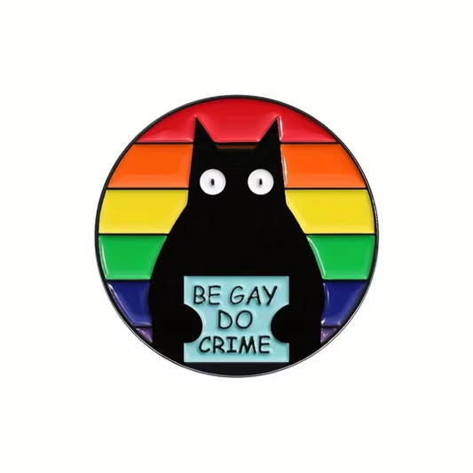 The Be Gay Do Crime Cat Pin by RainBee Designs LLC showcases a black cat holding a “Be Gay Do Crime” sign on a vivid, rainbow-striped background. This playful accessory is ideal for anyone looking to add unique, pride-inspired flair to their collection.