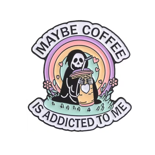 Enjoy a dose of dark humor with the “Maybe Coffee is Addicted To Me Pin” by RainBee Designs LLC, featuring a cartoon grim reaper sipping an oversized iced coffee amidst pastel rainbows and flowers. Playful text above and below declares, “Maybe coffee is addicted to me.”.