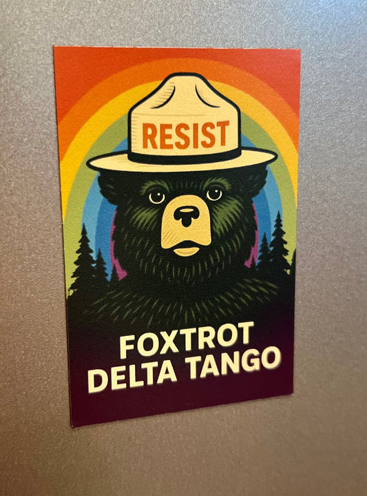 A vibrant FDT Magnet by RainBee Designs LLC features a bear in a ranger hat labeled RESIST, with rainbow and tree background, and FOXTROT DELTA TANGO text. This waterproof vinyl fridge magnet is perfect for brightening any space.