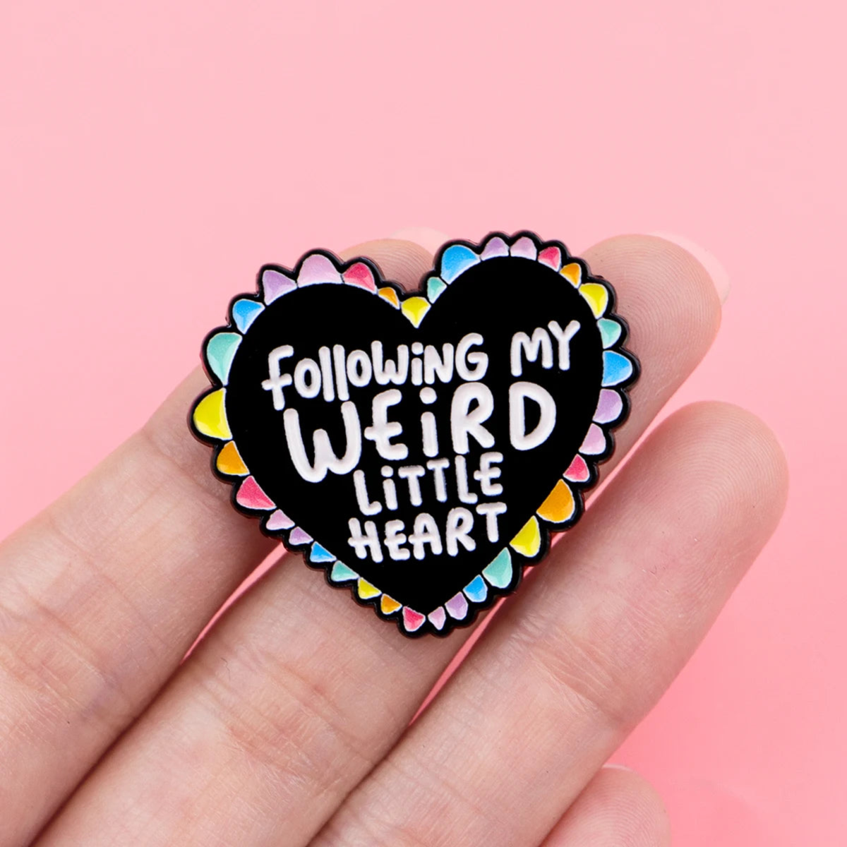 Heart-shaped pin with 'Following my weird little heart' text on a pink background
