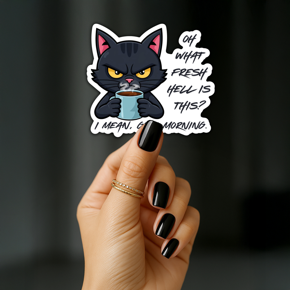 A hand with black nail polish holds a die-cut sticker featuring a grumpy black cat holding a blue mug with the text 'OH WHAT FRESH HELL IS THIS? I MEAN GOOD MORNING.' against a dark blurred background.
