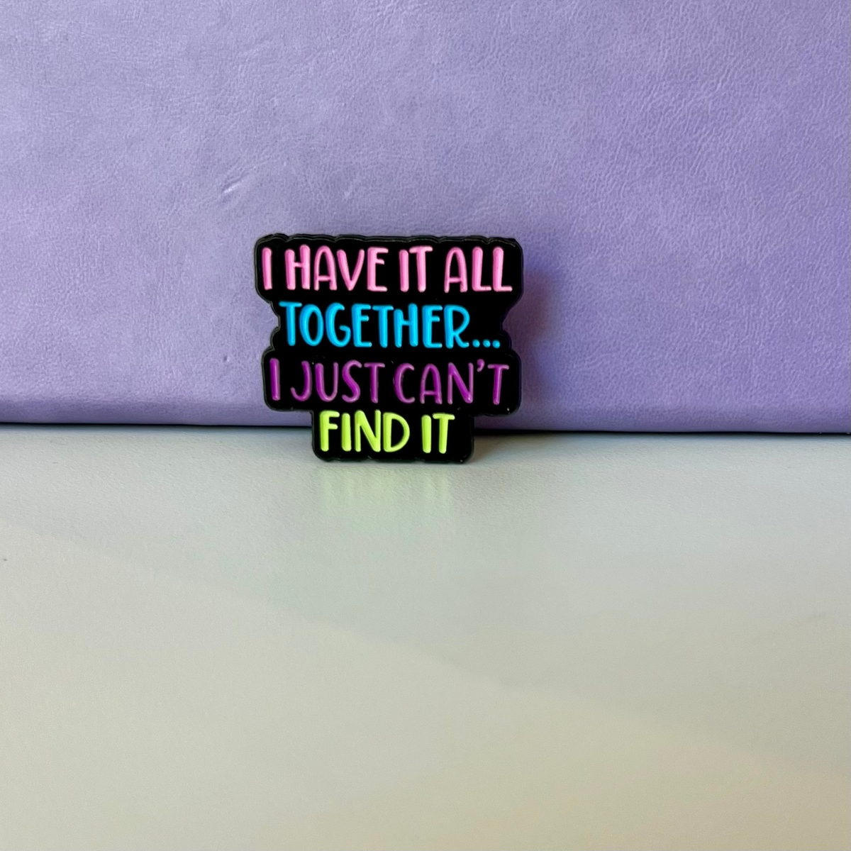 A small enamel pin with the text 'I HAVE IT ALL TOGETHER... I JUST CAN'T FIND IT'