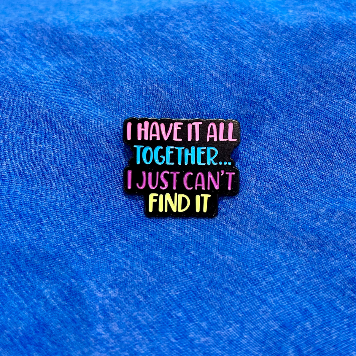 A small enamel pin with the phrase 'I HAVE IT ALL TOGETHER... I JUST CAN'T FIND IT'