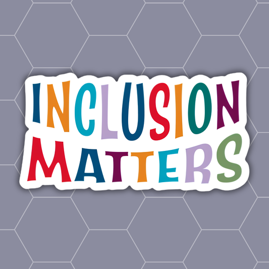 A die-cut sticker with the words 'INCLUSION MATTERS' in colorful, playful lettering on a white background, set against a gray hexagonal patterned backdrop.