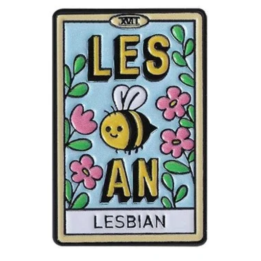A rectangular embroidered patch with a light blue background, featuring the words “LES" with a smiling cartoon bee between the letters "AN" in large yellow letters and pink flowers, green leaves, and a black border. The letters “XVT” appear at the top. The word "LESBIAN" appears at the bottom. 