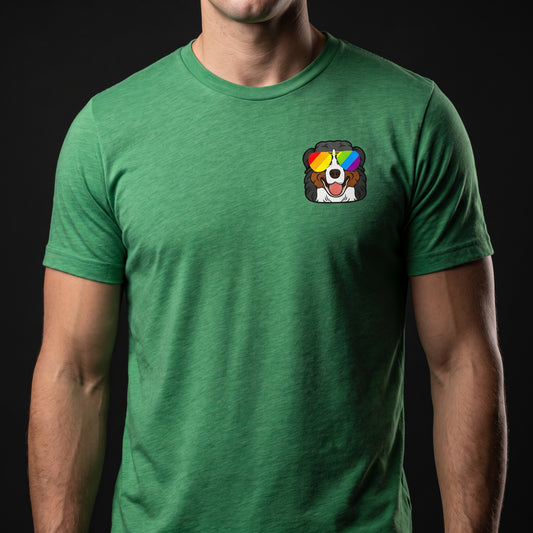 A person wearing the RainBee Designs LLC Berner Pride T-Shirt, which features a small cartoon Bernese Mountain Dog with rainbow sunglasses on the left chest, set against a black background.