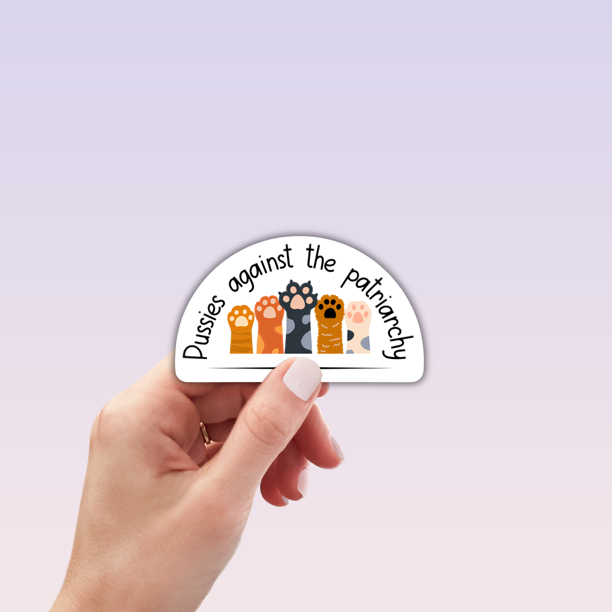 A hand holds the "Pussies Against the Patriarchy Sticker" by RainBee Designs LLC—this vinyl waterproof sticker shows five unique cat paws with playful text above, perfect for expressing your feminist style and beliefs.