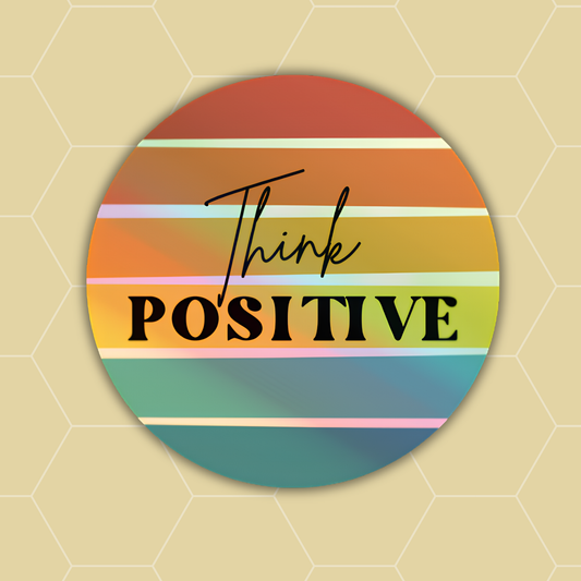 A round sticker or button featuring the text 'Think POSITIVE' in black over a retro rainbow-striped background, centered on a beige hexagonal patterned backdrop.