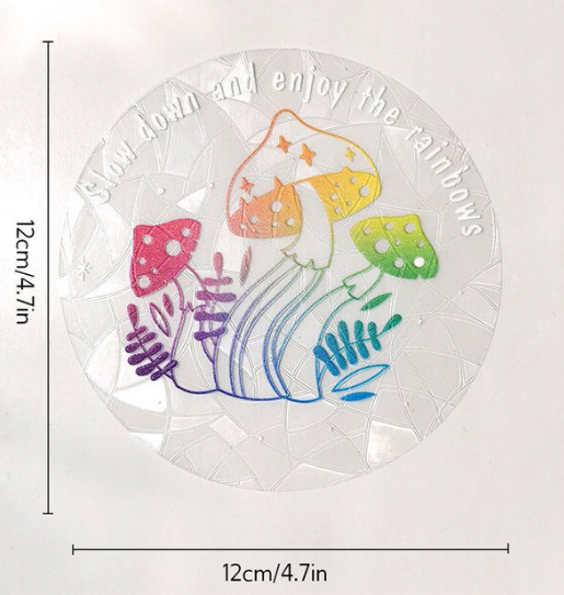 Introducing the Mushroom Suncatcher by RainBee Designs LLC—a round window decal adorned with colorful mushrooms, purple plants, and the phrase “slow down and enjoy the rainbows.” This vibrant sticker doubles as a delightful rainbow window decal or sun catcher, bringing a whimsical touch to any space. Dimensions: 12cm x 12cm (4.7in x 4.7in).